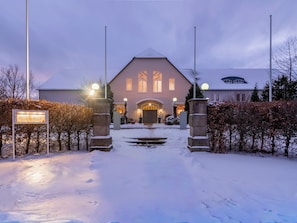 A hotel entrance with a snow-covered path leading to a building with a large arched doorway and multiple windows. - Golfhotel Fahrenbach (Trostau)