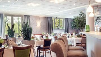 A restaurant with multiple tables, chairs, and potted plants.