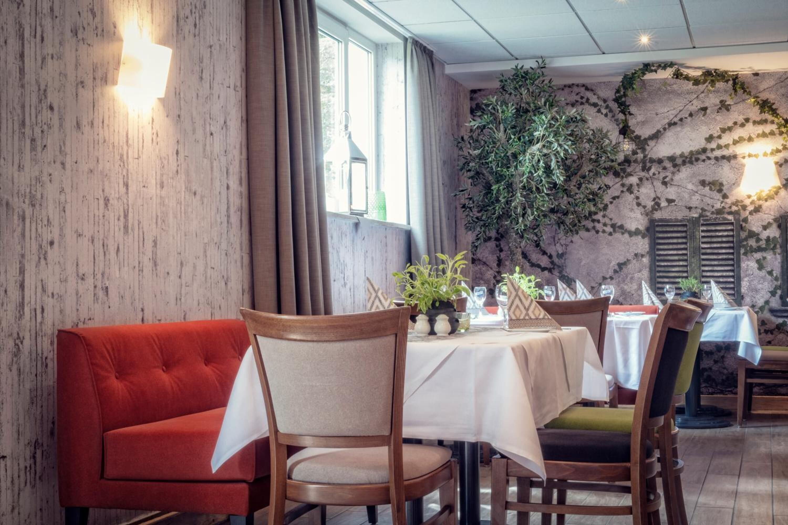 A dining area with a red sofa, wooden chairs, and tables set for dining.