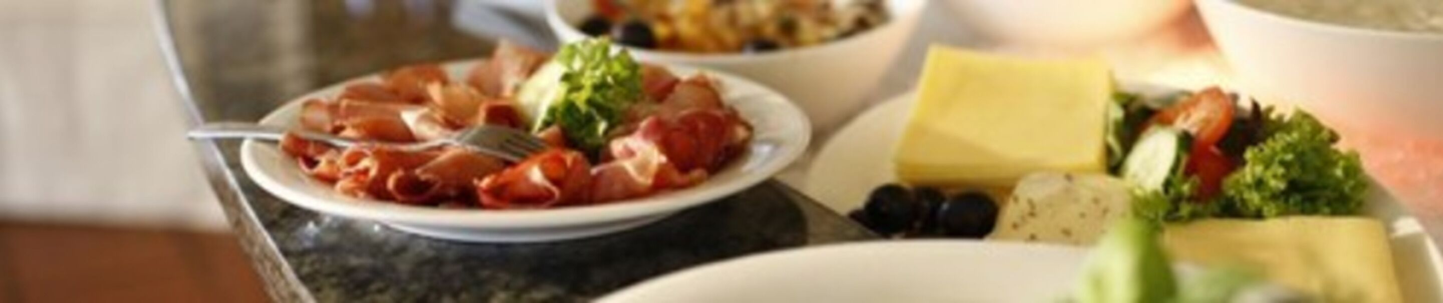 Una mesa de comedor con platos de comida, incluyendo carnes y verduras.
