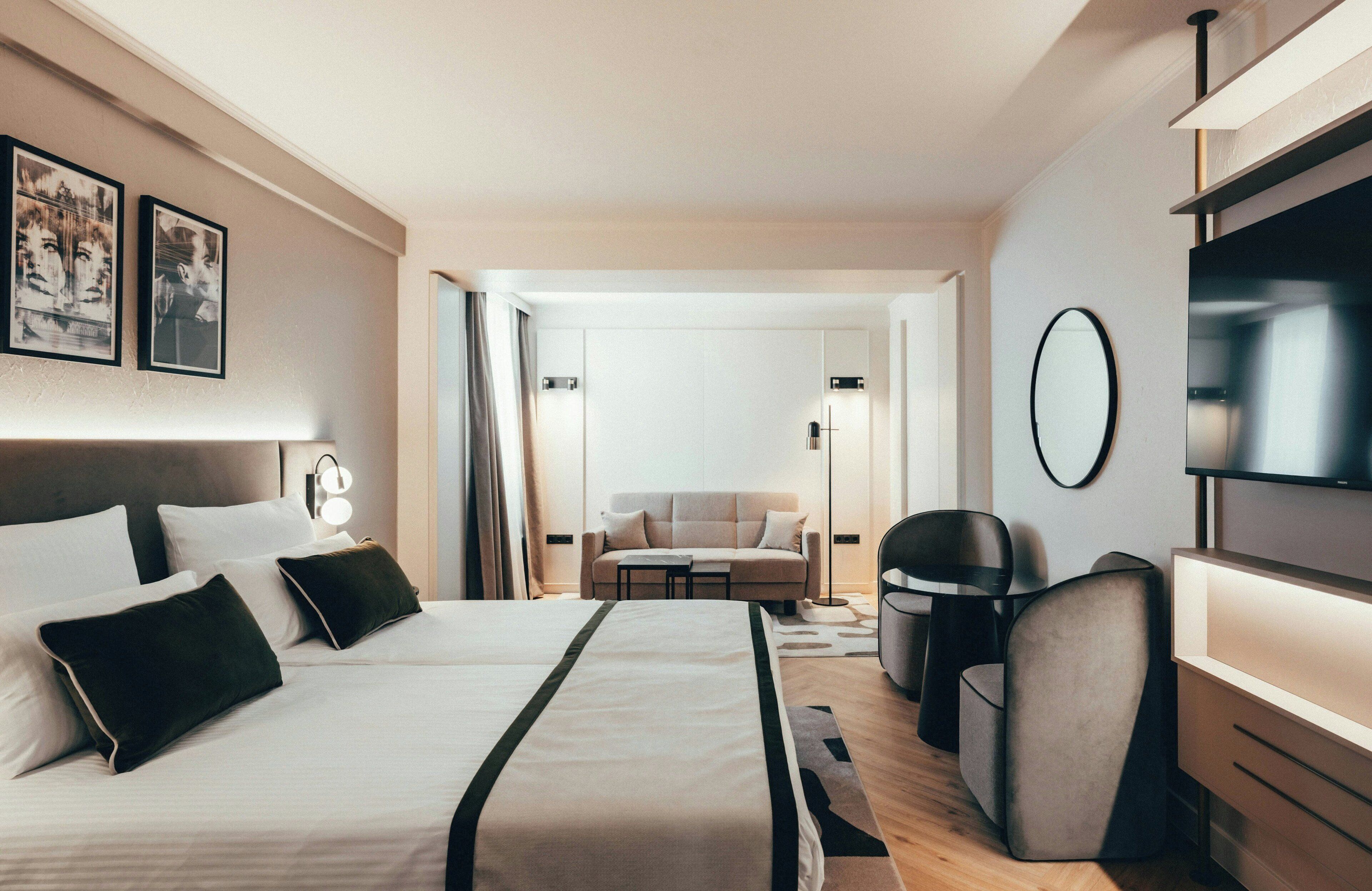 Una habitación de hotel con cama, sofá, televisión y escritorio.