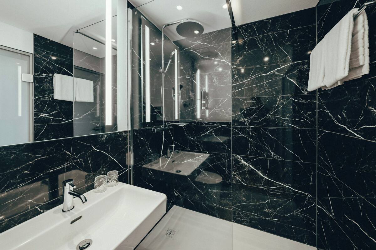 A modern bathroom with a large mirror, a sink, and a shower area.