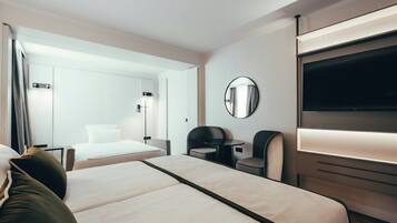 Ein modernes Hotelzimmer mit Bett, Schreibtisch, Stuhl, Fernseher und Spiegel.