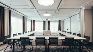 Ett konferensrum med ett långt bord, svarta stolar och ett heltäckningsmatta på golvet.