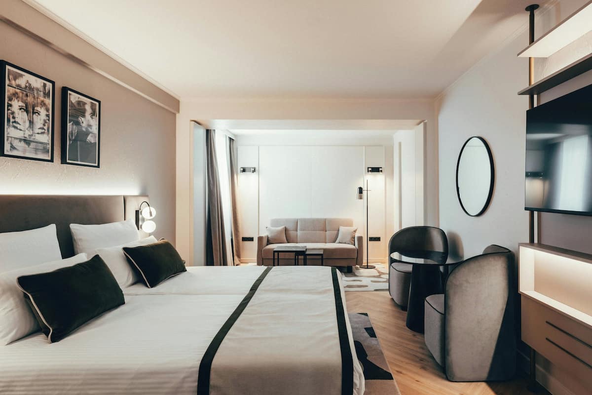 A hotel room with a bed, a sofa, a TV, and a desk.