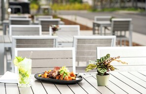 A dining table with a plate of food, a drink, and a potted plant. - Leonardo Hotel Köln (Cologne)
