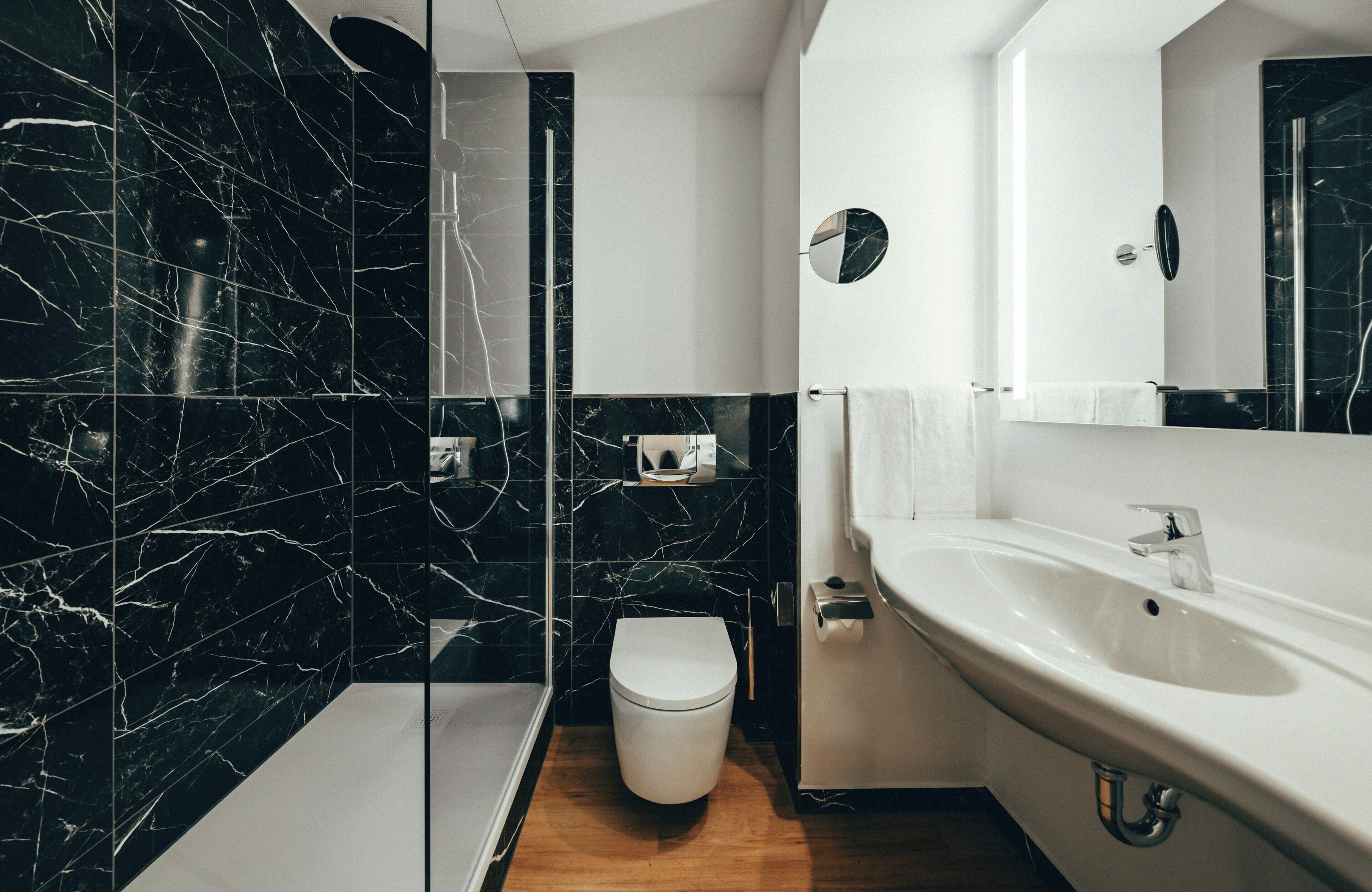 Un baño moderno con tocador de mármol, inodoro y zona de ducha.