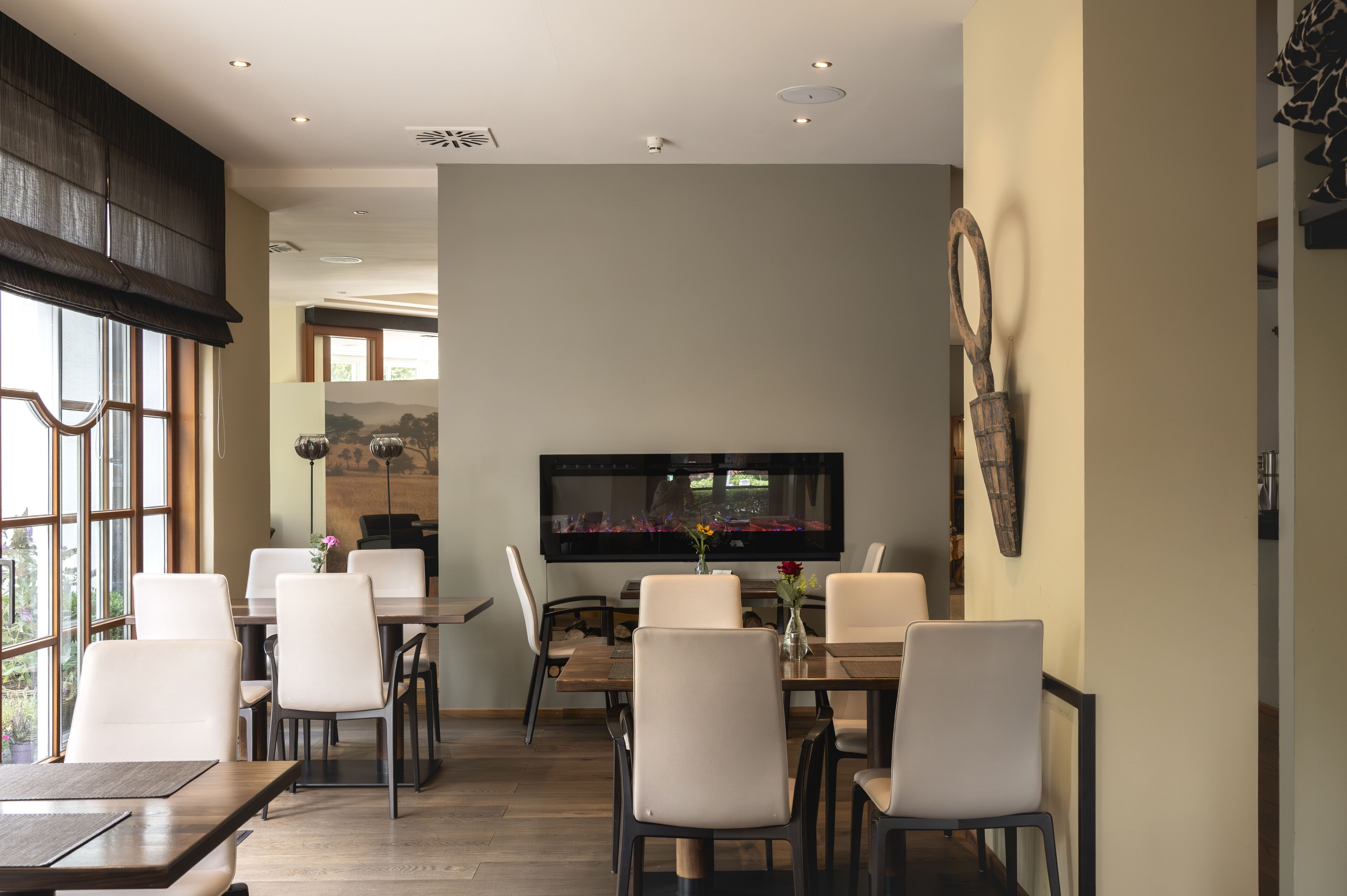 A dining area with a large flat-screen TV, white chairs, and a wooden table.