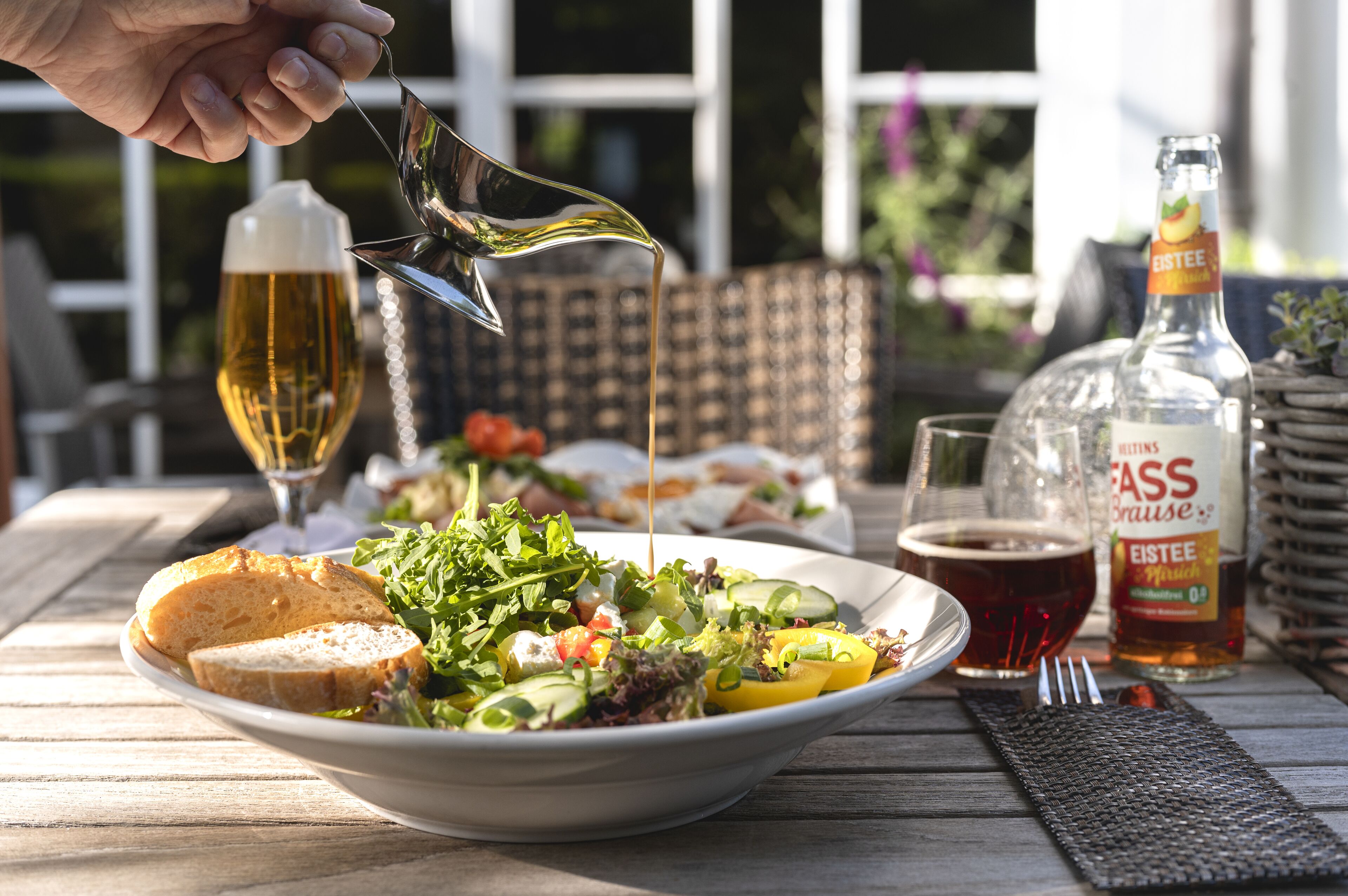 Una mesa con ensalada, pan, una botella de Essée y una jarra de cerveza.