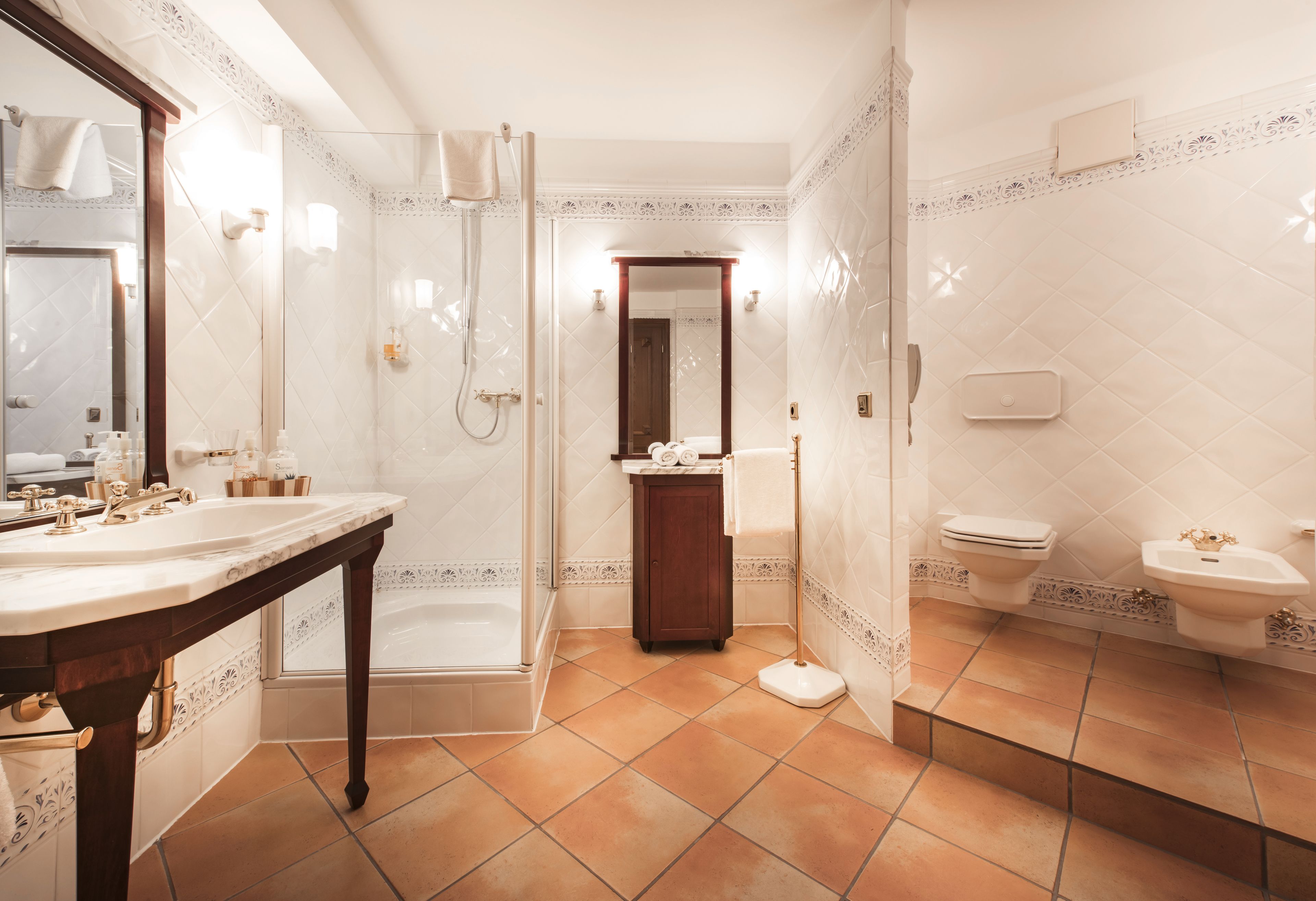 Un baño con un espejo grande, dos lavamanos, una bañera y un inodoro.