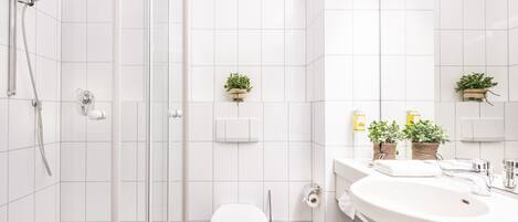 Un baño moderno con ducha de vidrio, inodoro blanco y un lavamanos grande con espejo.