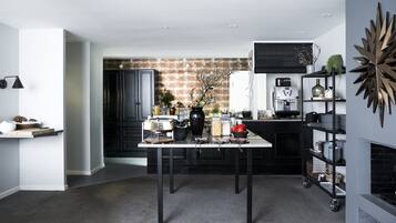 Una cocina moderna con una mesa de comedor, armarios negros y una cafetera.