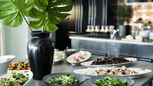 A dining table with various dishes and a large black vase with a plant. - Skjalm Hvide Hotel (Slangerup)