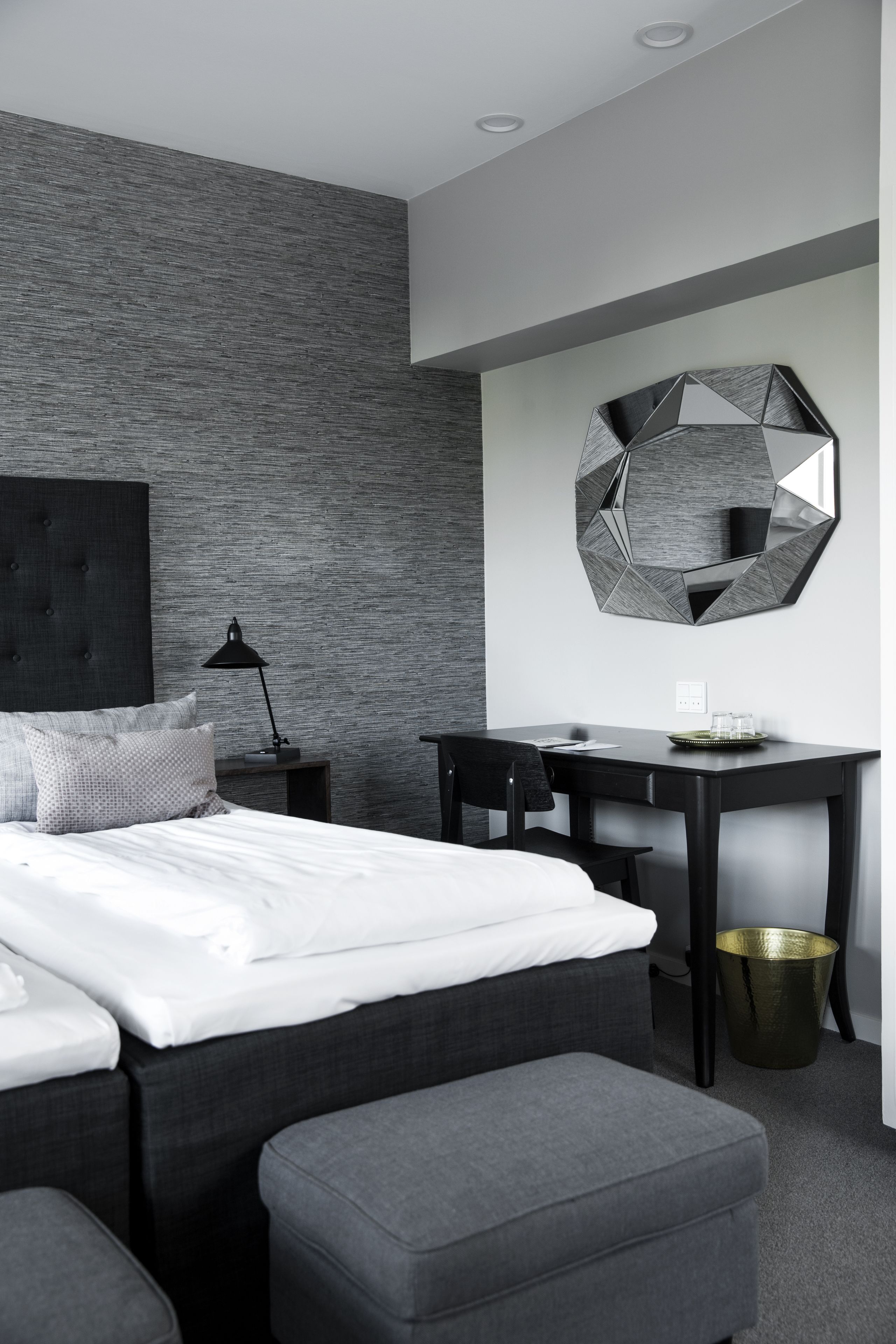 Quarto moderno com cama, escrivaninha e um espelho grande.