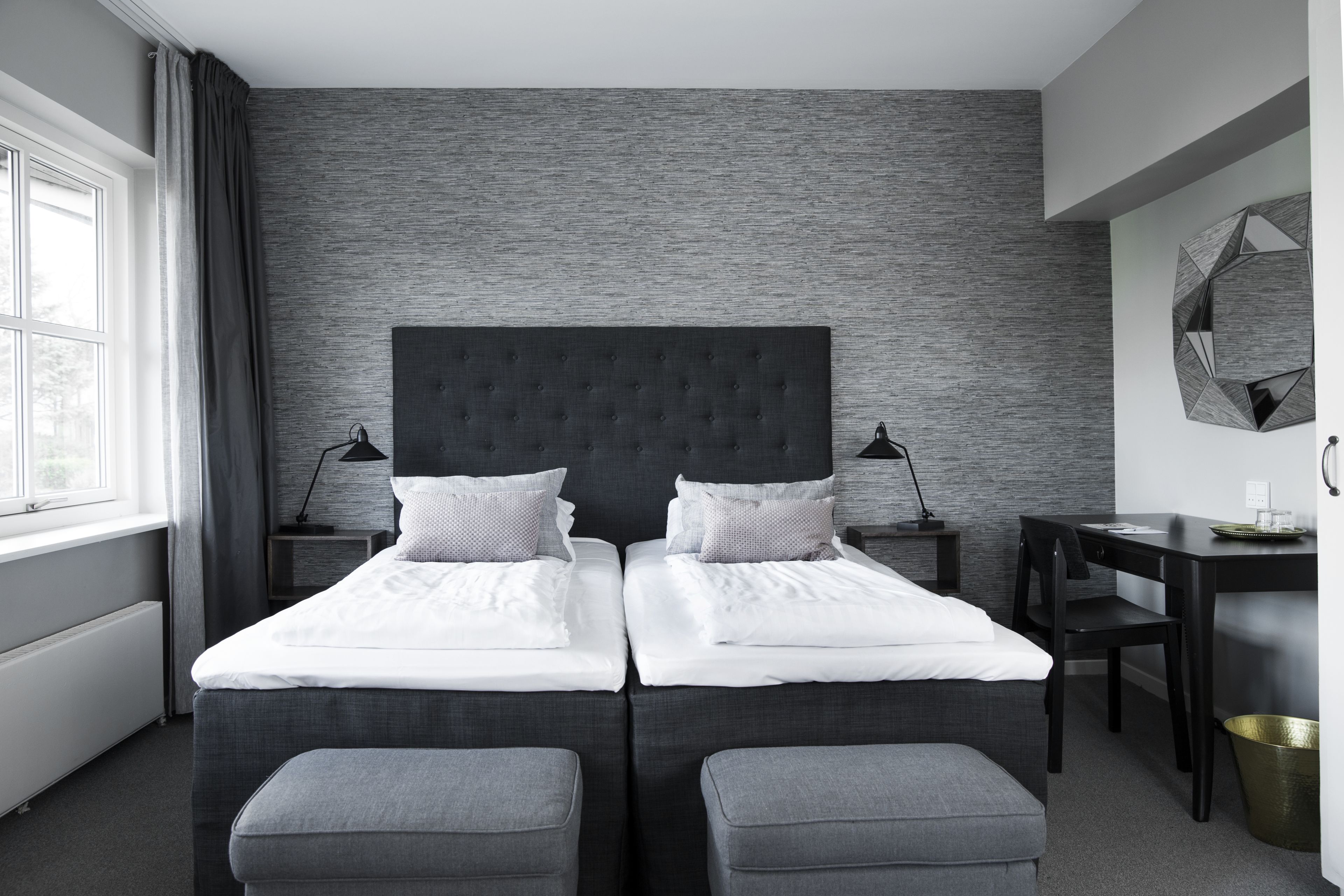 A modern hotel room with a large bed, two bedside tables, a desk, and a chair.