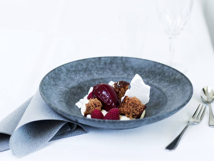Un postre sobre un plato oscuro, con un tenedor y una cuchara a un lado.