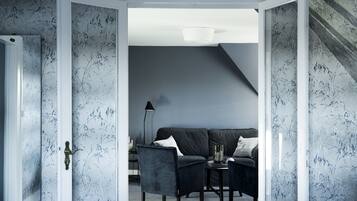 A modern living room with a dark blue sofa, two armchairs, and a small table with a vase.