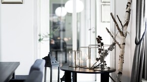 A modern interior with a round table displaying glass vases and a birch branch sculpture. - Skjalm Hvide Hotel (Slangerup)