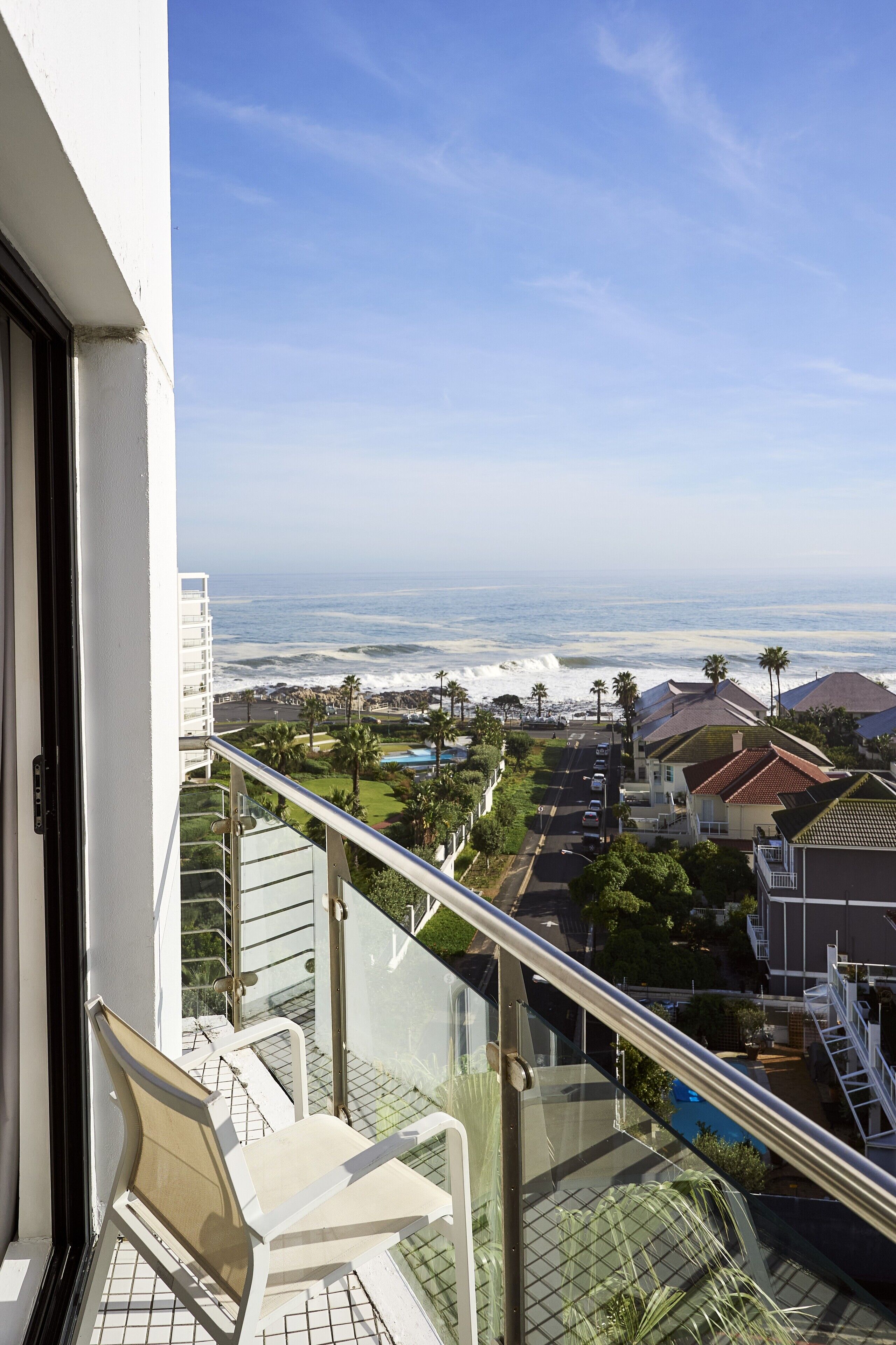 Een balkon met uitzicht op de oceaan en een woonwijk.