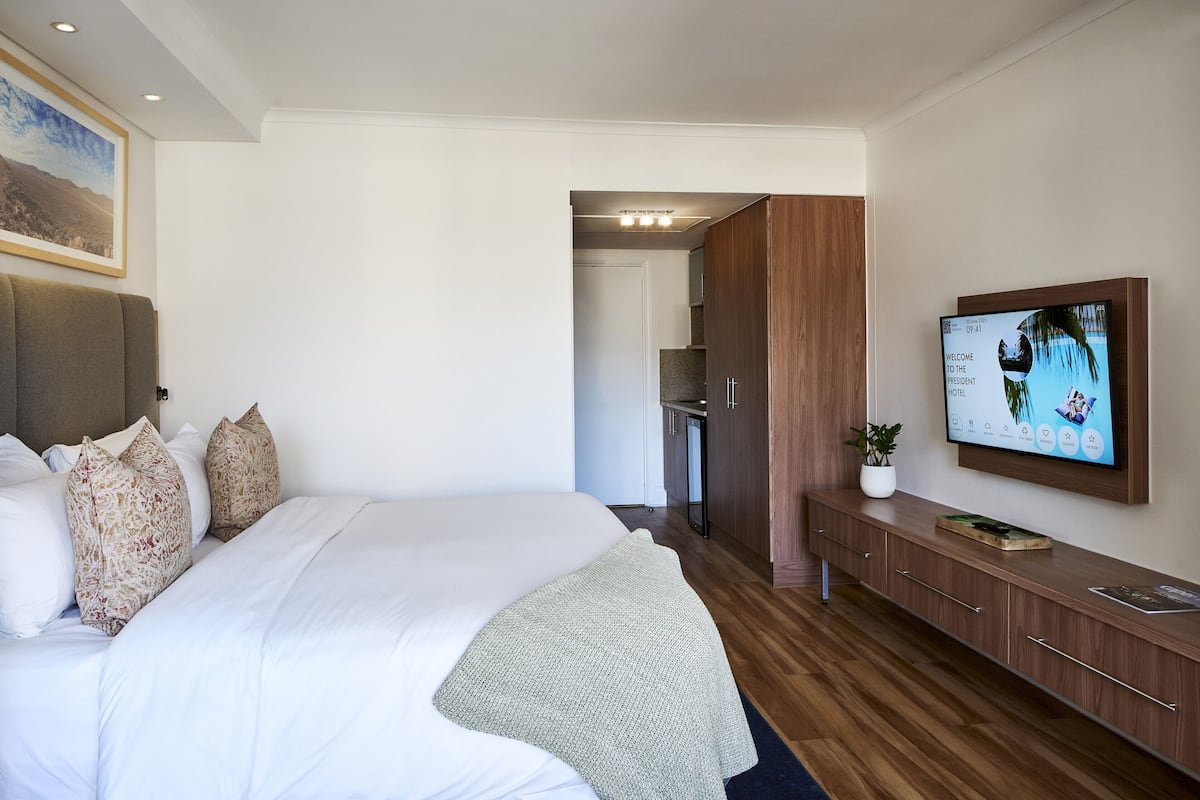 Ein modernes Hotelzimmer mit einem großen Bett, einem an der Wand befestigten Fernseher und einem Holzschrank.