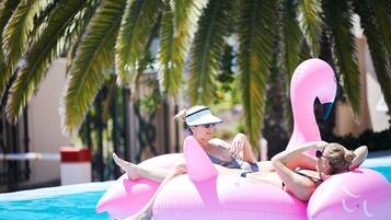 Een buitenzwembad, parasols bij het zwembad en ligstoelen