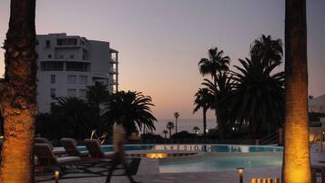 Una piscina al aire libre, sombrillas, sillones reclinables de piscina