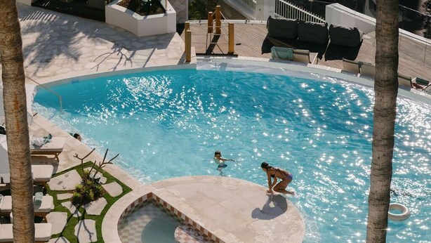 A pool area with lounge chairs and umbrellas, surrounded by palm trees. - President Hotel (Cape Town)