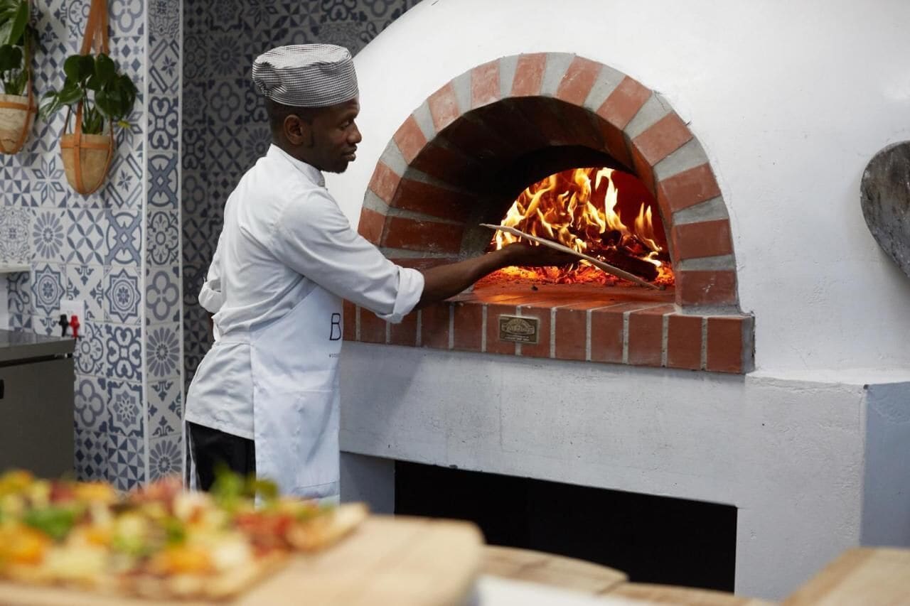 A chef operating a brick oven pizza oven.