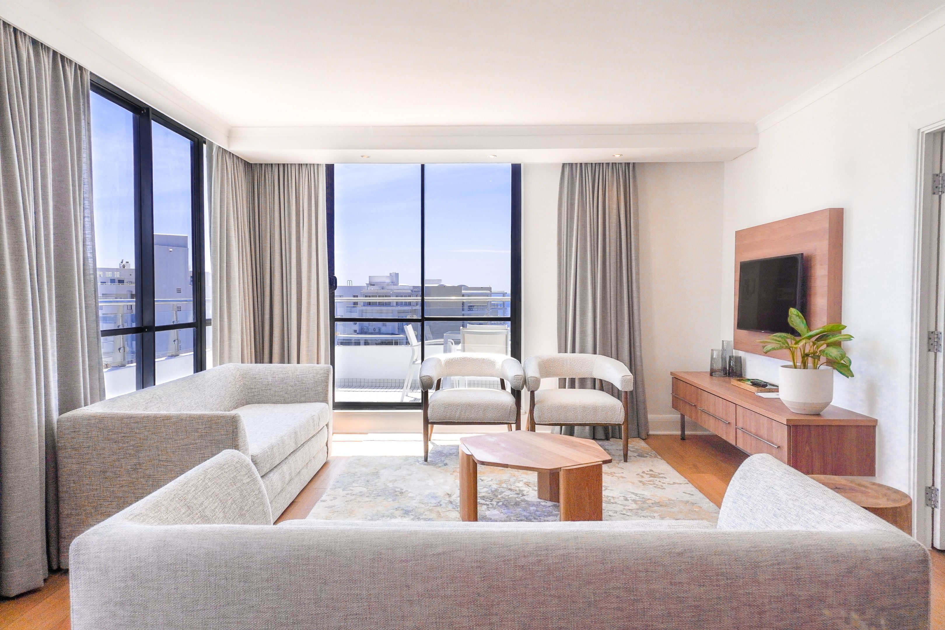 A modern living room with a sofa, armchairs, a coffee table, and a TV.