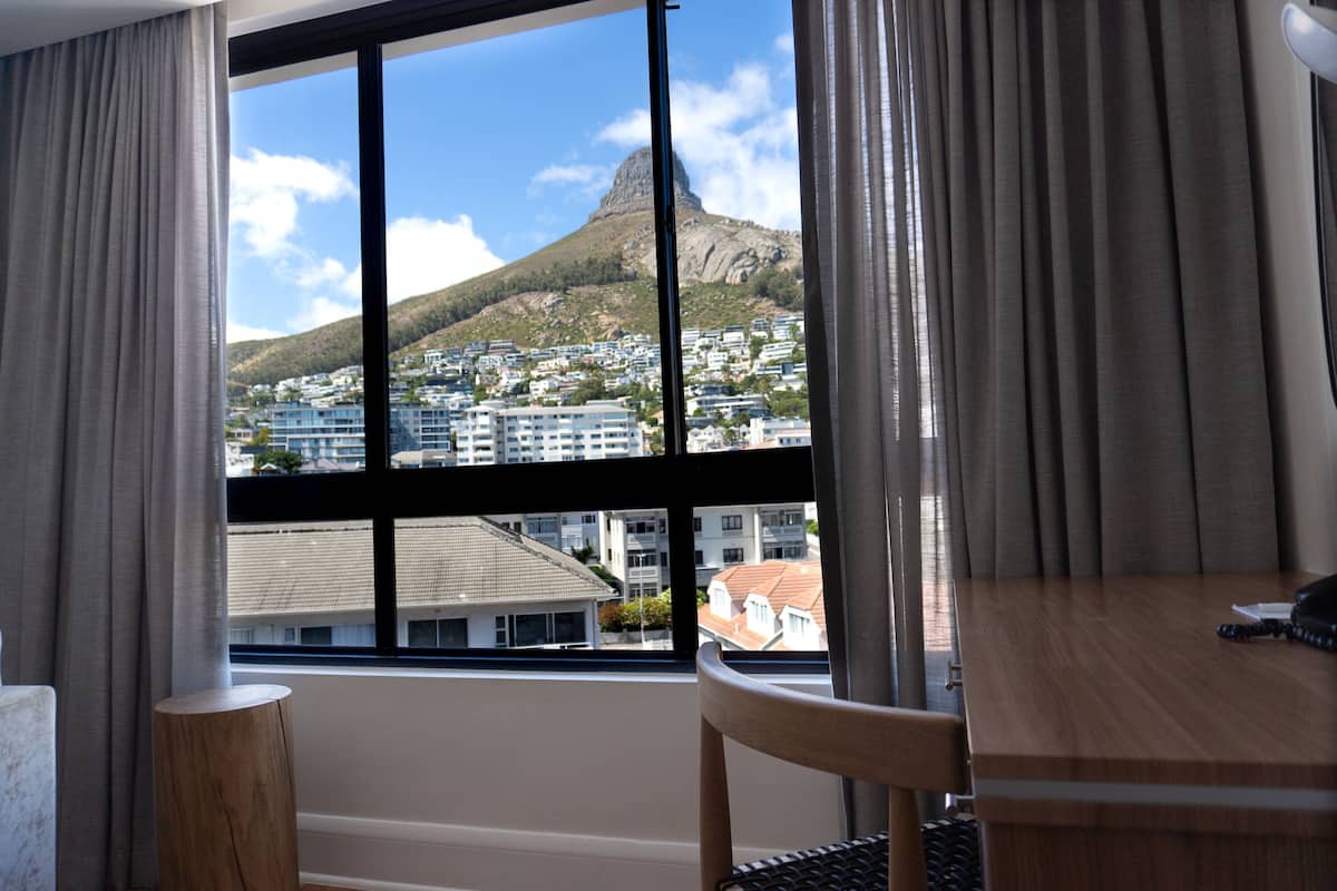 Ein Hotelzimmer mit großem Fenster und Blick auf Berg sowie Stadtlandschaft.