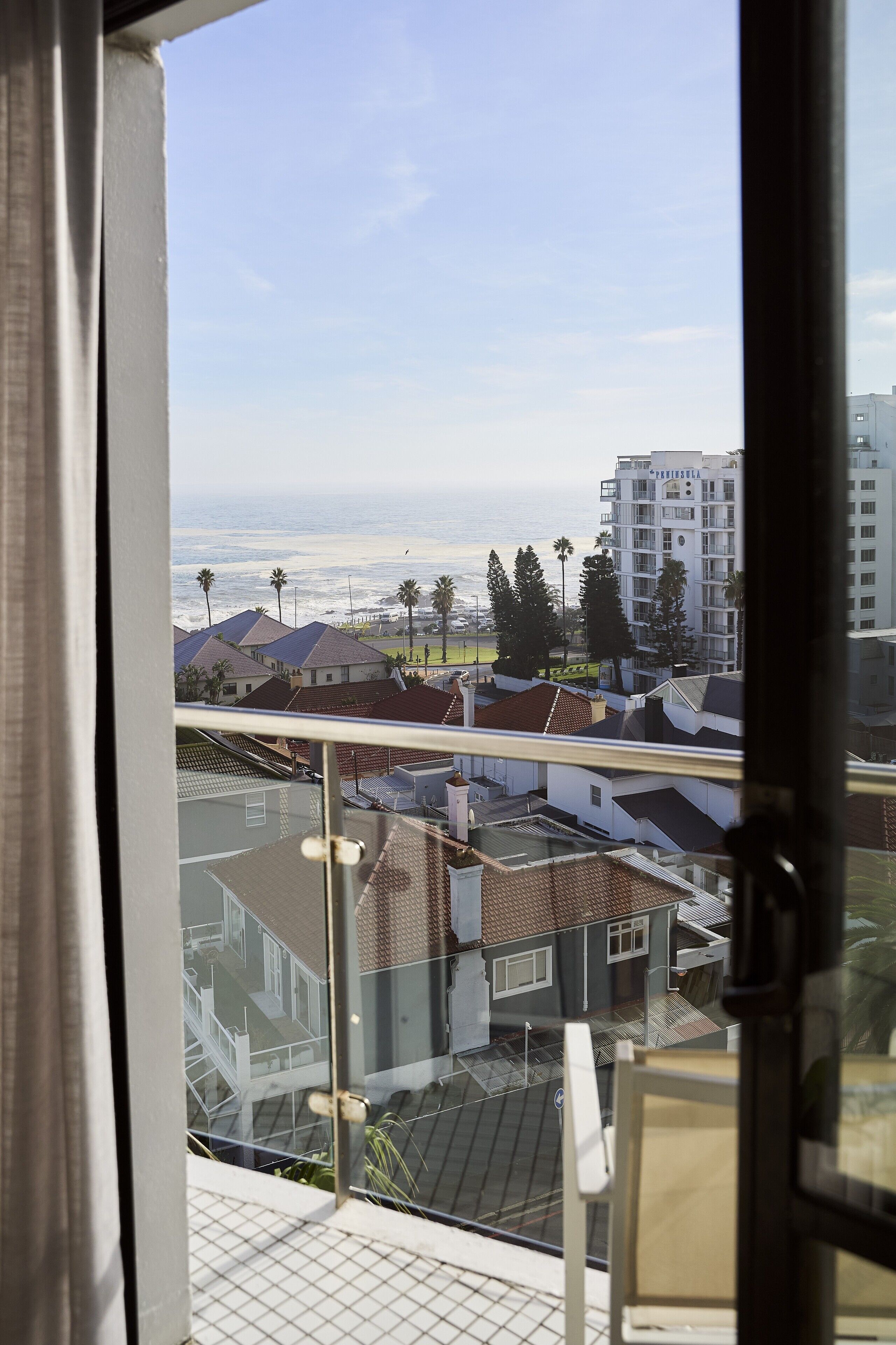 A balcony with a view of a residential area, including houses and a tall building.
