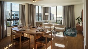 A modern hotel room with a dining area, a sofa, a lamp, and a view of the city. - President Hotel (Cape Town)