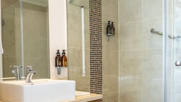 A modern bathroom with a large mirror, a white sink, and a glass-enclosed shower area.