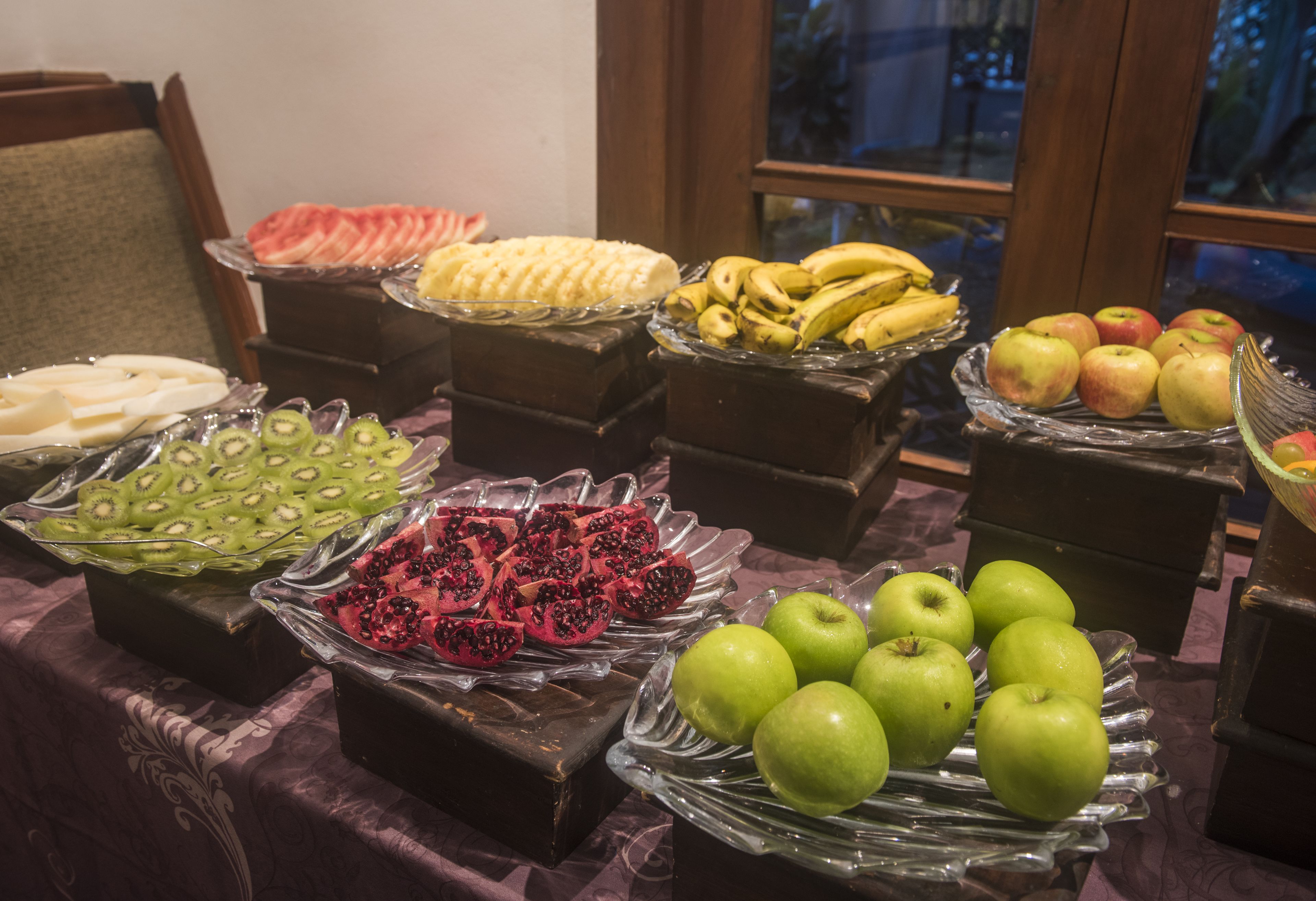 A buffet table with various fruits and desserts.