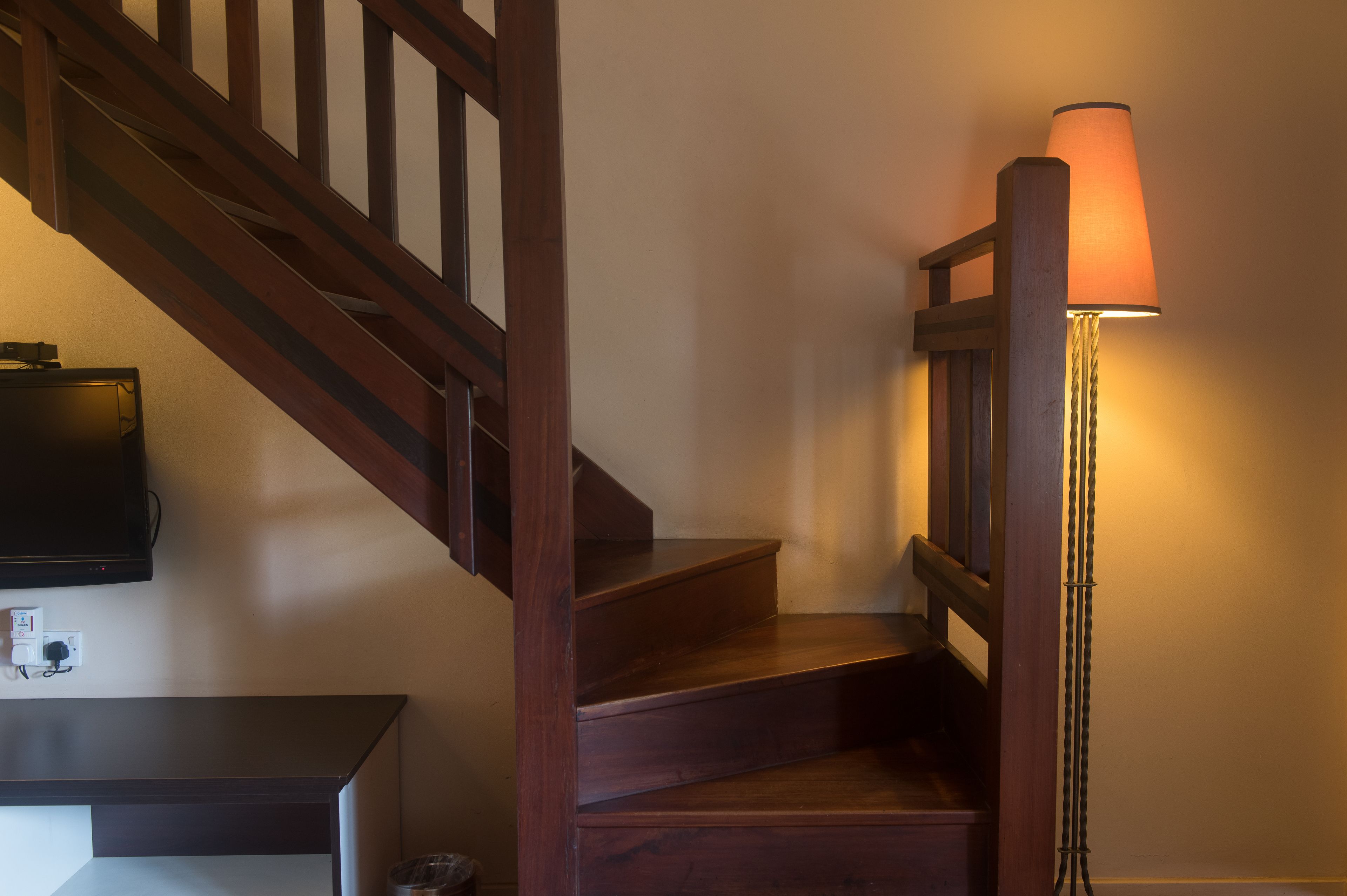 Una escalera de madera con una lámpara a la derecha.