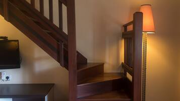 Una escalera de madera con una lámpara a la derecha.