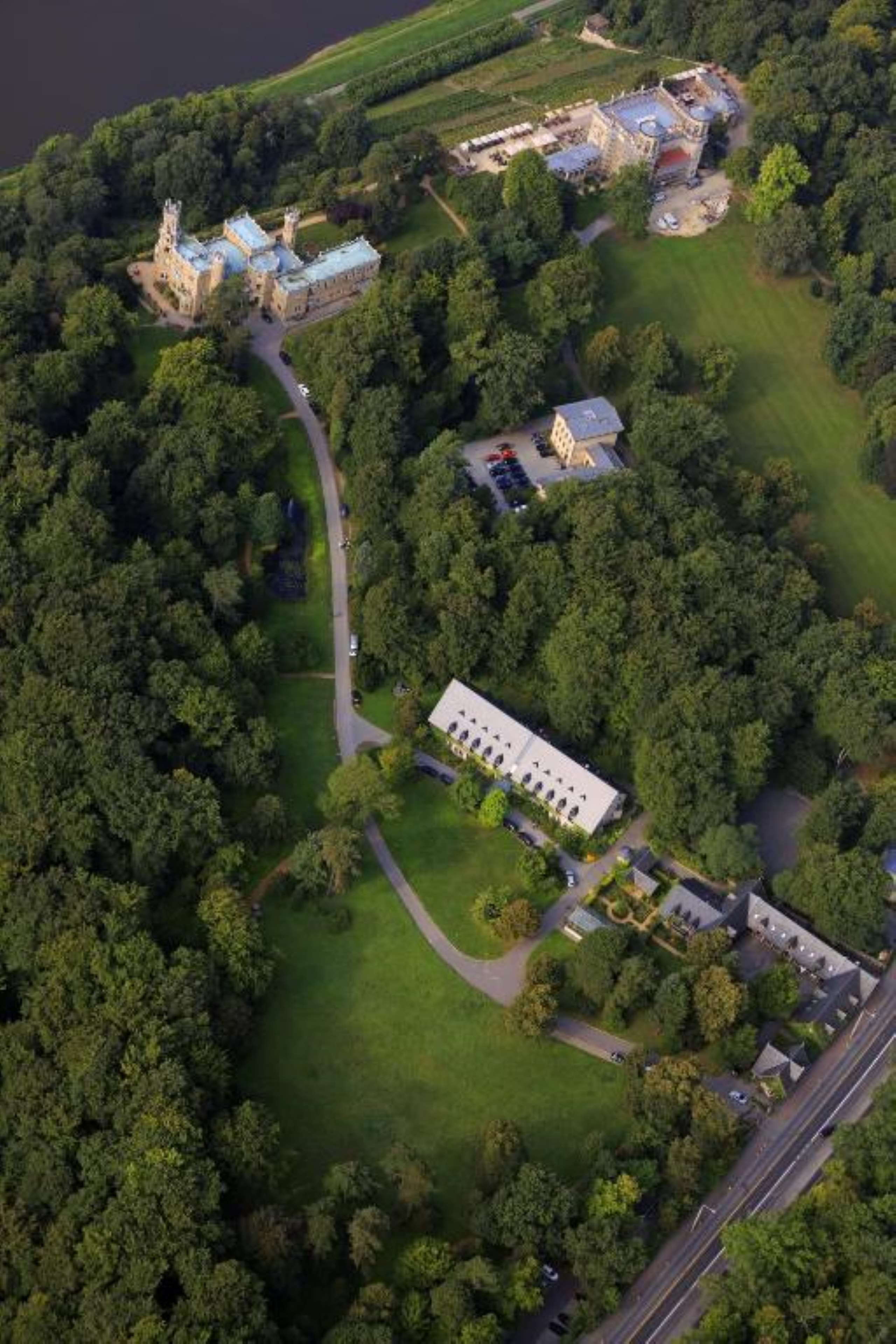 Luchtbeeld van een groot landgoed met een hoofdgebouw, verschillende kleinere gebouwen en uitgestrekte begroeiing.