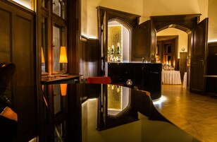A bar area with a glass table, red chairs, and a mirror reflecting the interior.