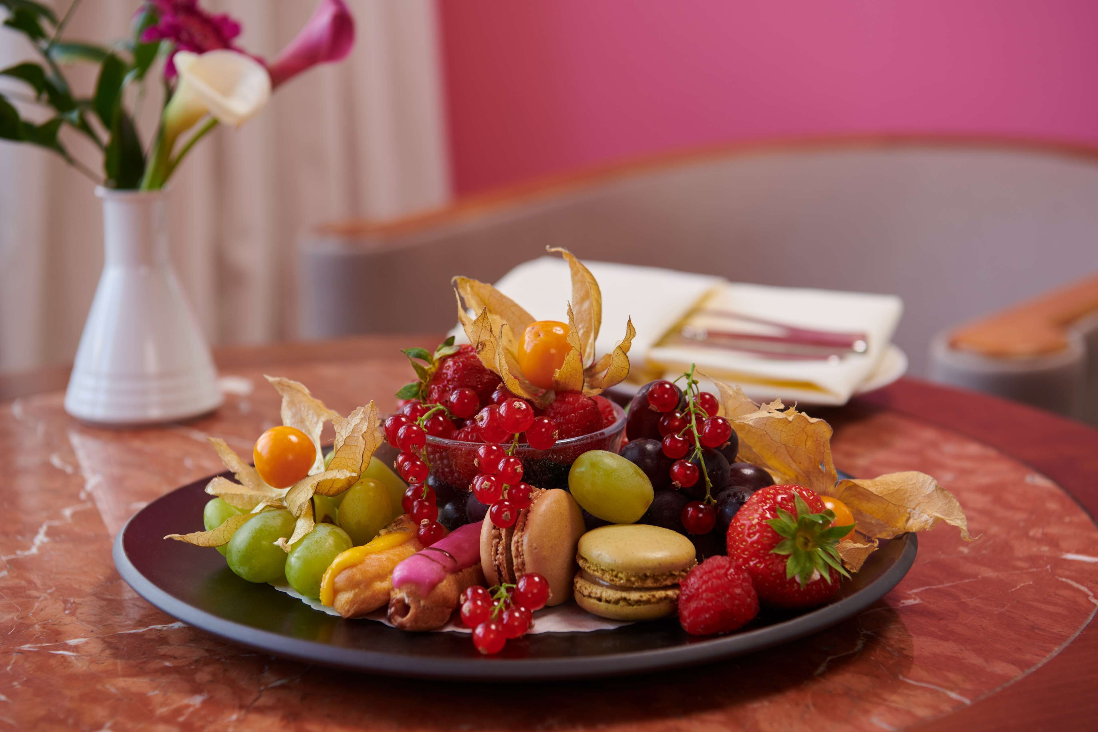 Uma travessa com frutas variadas e doces sobre uma mesa de mármore.