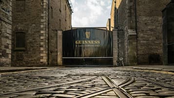 En brostensbelagt gade, der fører hen til et sort jerngitter med Guinness-logoet.