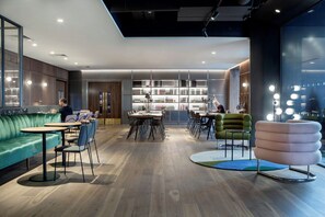 A modern interior with a green sofa, round tables, and a unique pink chair. - The Alex (Dublin)