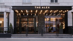 The exterior of The Alex hotel with a modern entrance, illuminated string lights, and a glass facade. - The Alex (Dublin)