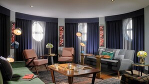 A modern living room with a green sofa, two armchairs, a grey sofa, a wooden coffee table, and a patterned rug. - The Alex (Dublin)