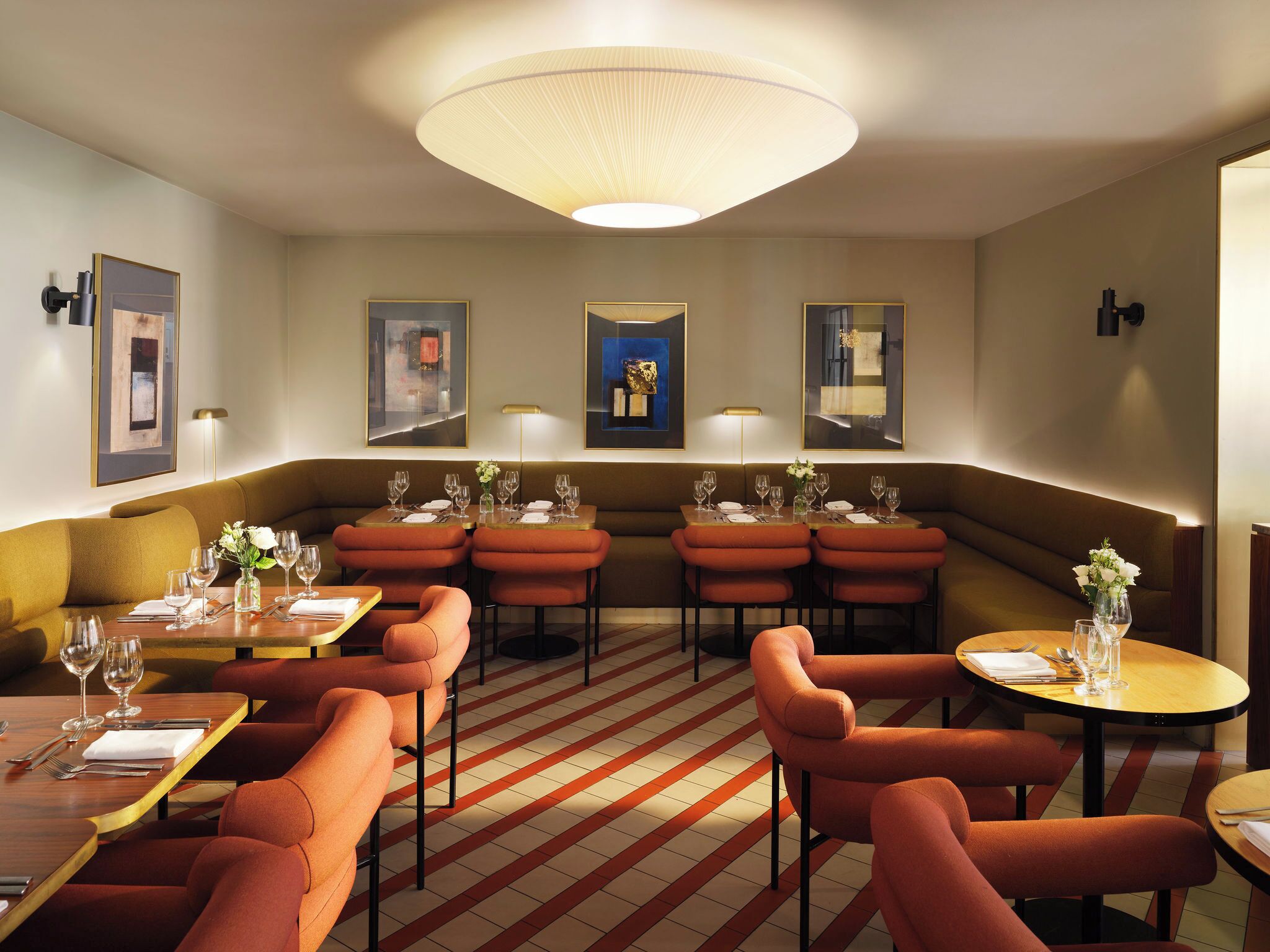 A modern dining area with booths and tables, featuring a striped floor pattern and contemporary decor.