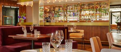 A bar area with a variety of liquor bottles, a seating area with tables and chairs, and a decorative light fixture.