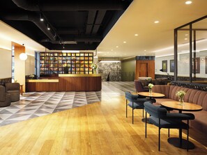 A reception area with a wooden reception desk, seating area with sofas and tables, and a patterned floor.