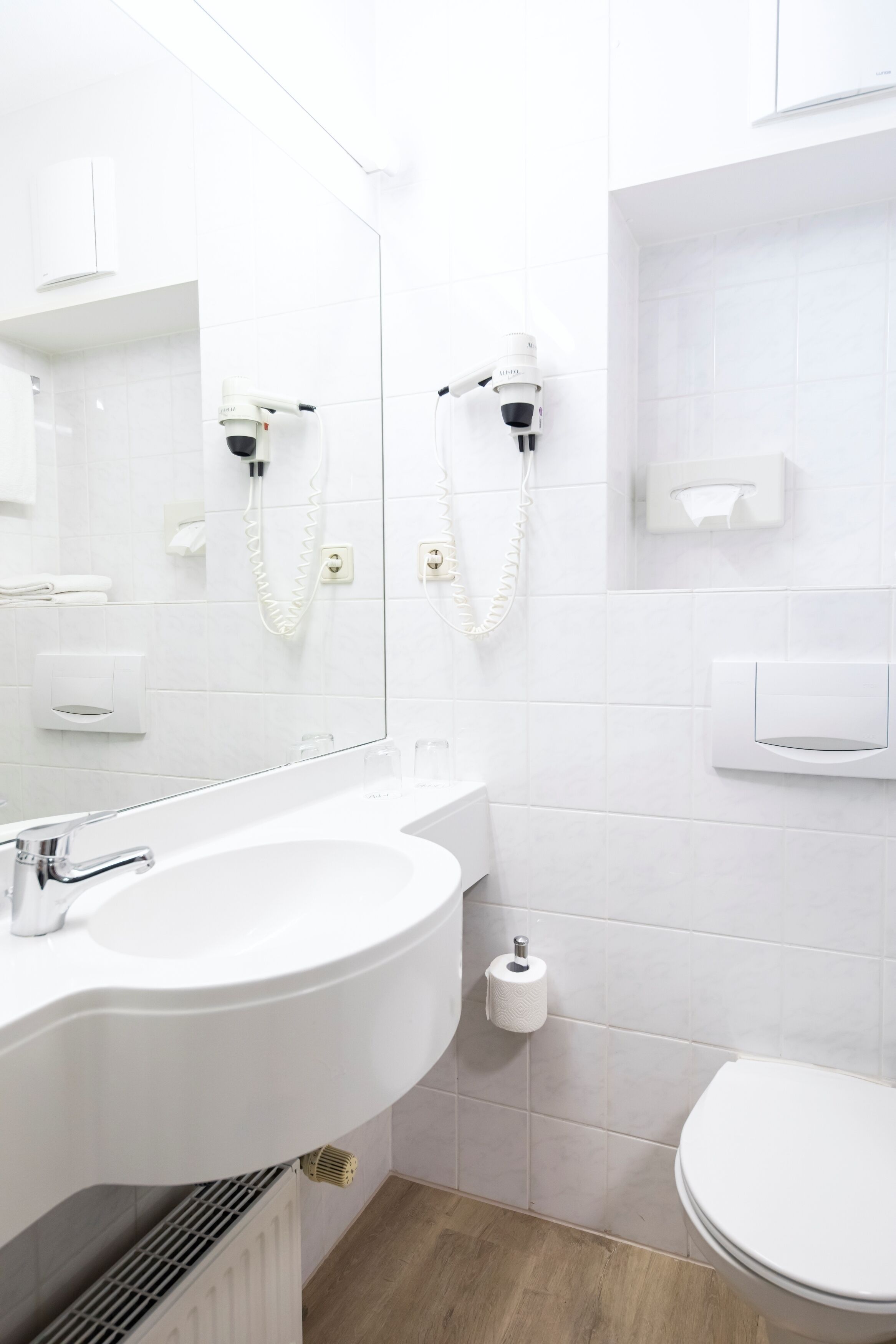 A modern bathroom with a white sink, mirror, and toilet.