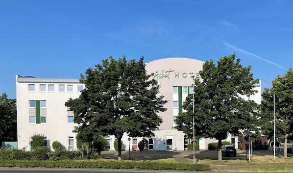 A modern hotel building with a sign reading "Achat Hotel."