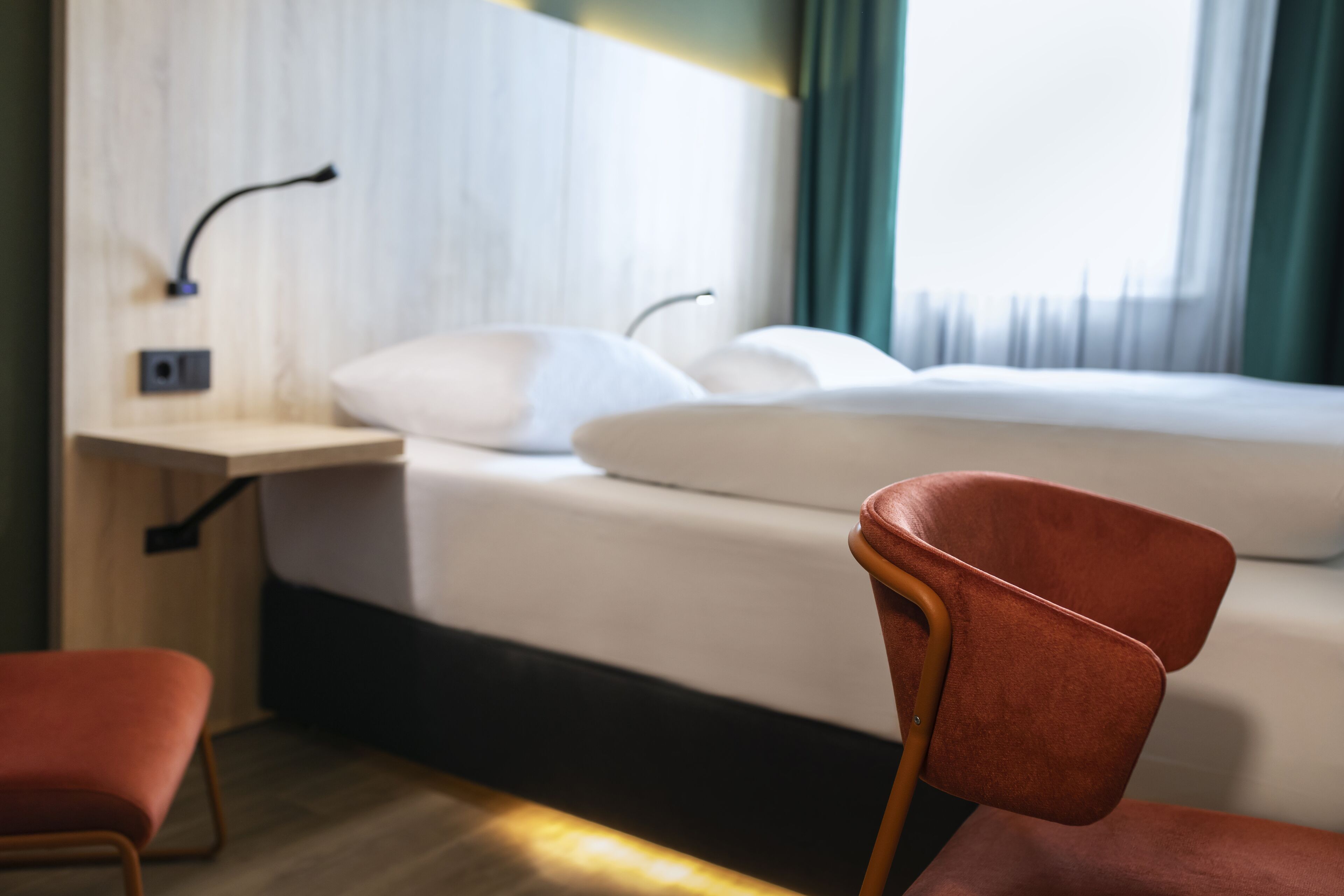 A hotel room with a bed, a desk, and a chair.