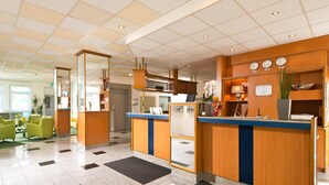 A hotel reception area with a check-in counter, seating area, and a view of the lobby.